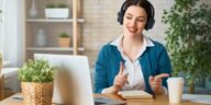 woman with headphones talking in front of a laptop