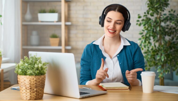 woman with headphones talking in front of a laptop