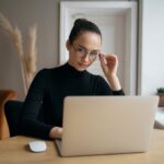 stylish woman with glasses reading on a laptop