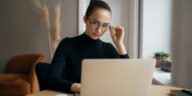 stylish woman with glasses reading on a laptop