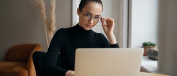 stylish woman with glasses reading on a laptop