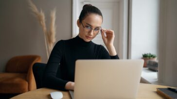 stylish woman with glasses reading on a laptop