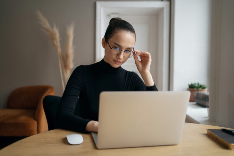 stylish woman with glasses reading on a laptop