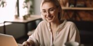 young blonde woman smiling working on a laptop at home