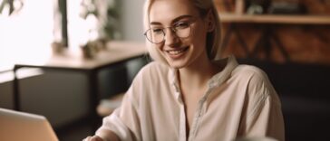 young blonde woman smiling working on a laptop at home