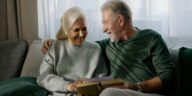 two grandparents holding a book sitting on a sofa