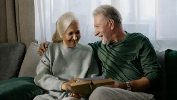 two grandparents holding a book sitting on a sofa