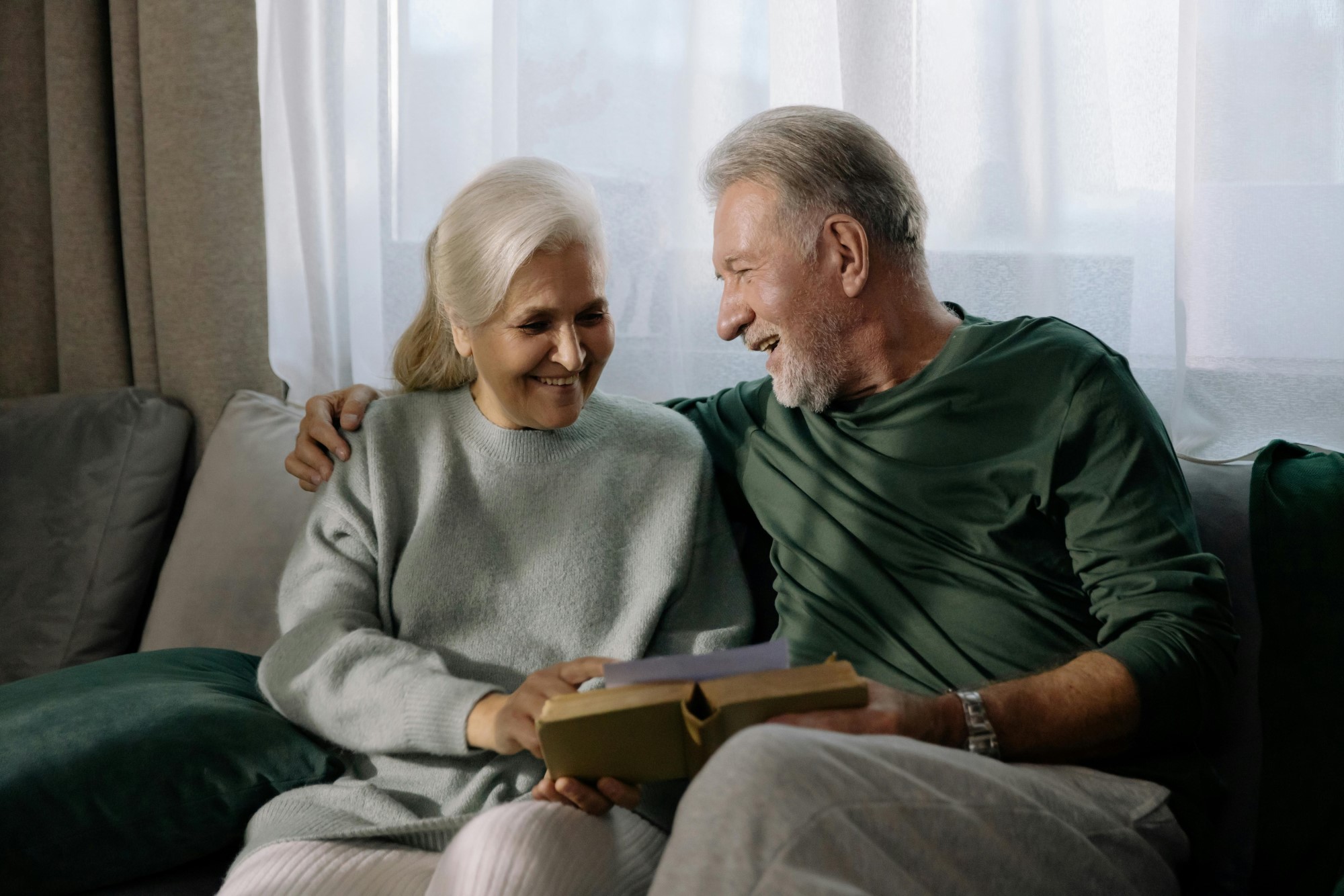two grandparents holding a book sitting on a sofa